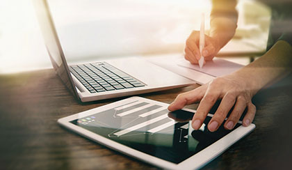 A person using their computer and tablet device.